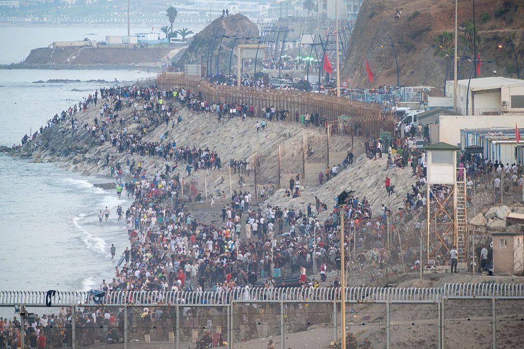 Decenas de migrantes intentan cruzar la frontera entre Ceuta y Marruecos el 31 de julio de 2026. En las horas previas, miles de personas habían llegado a la ciudad autónoma española desde Marruecos por mar y a pie, bordeando el rompeolas que separa ambos territorios.