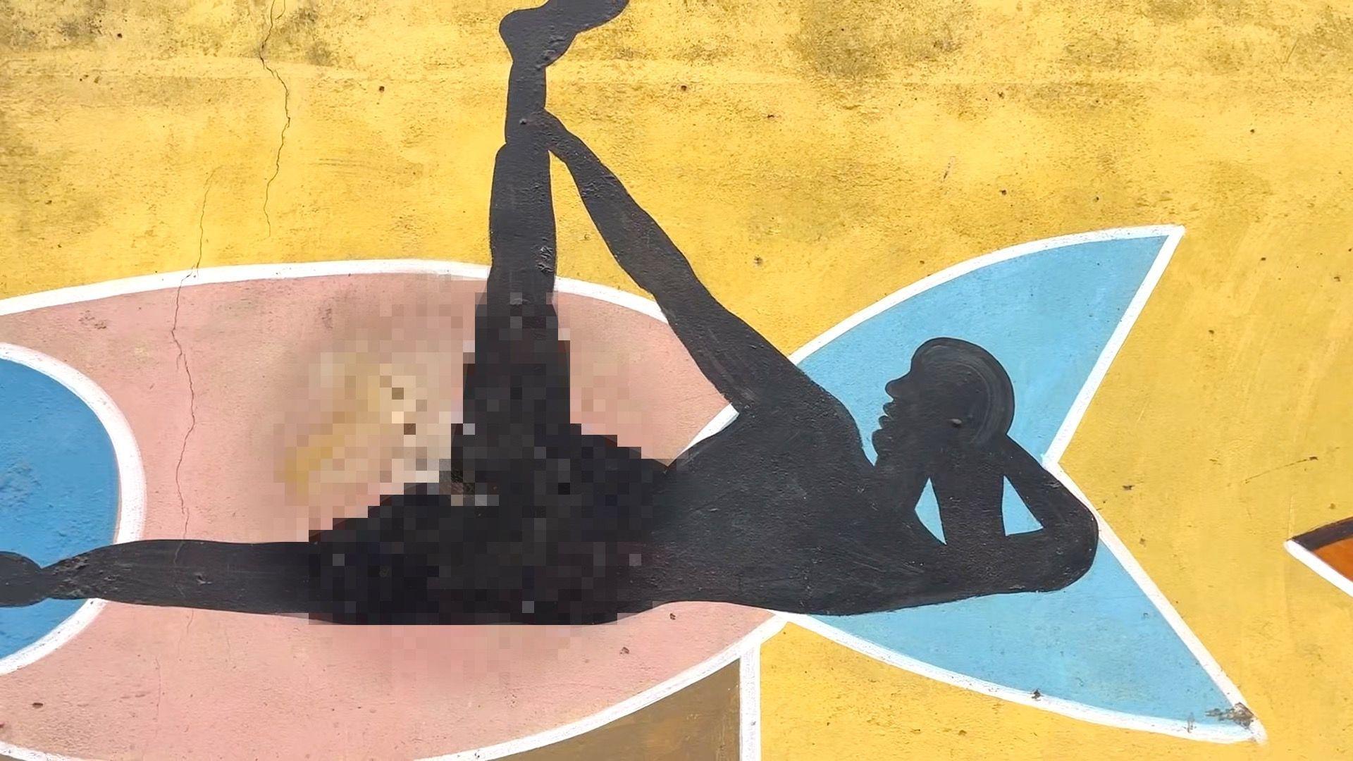 رسم جداري لجسد أنثى تلعب اليوغا، شوهت بخدش على منطقة تناسلية، الخدش تم تظليله.