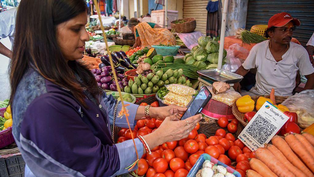 Mulher escaneando QR Code do Google Pay em uma banca de legumes