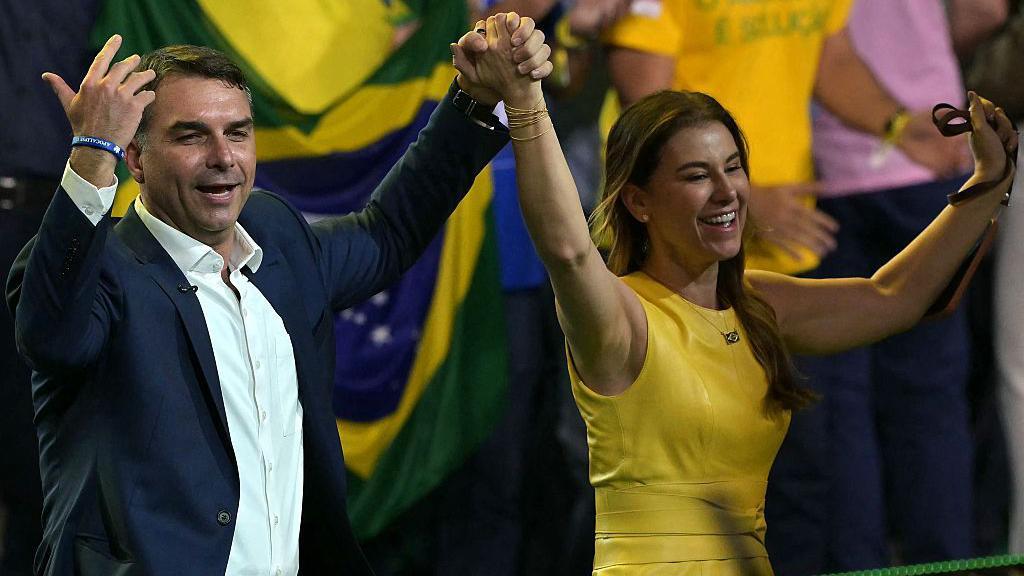 Fl&aacute;vio Bolsonaro e Fernanda Bolsonaro no palco. 