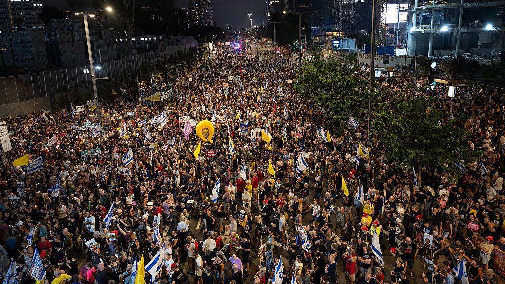 Multitudes de manifestantes portan banderas y pancartas expresando su opinión en Tel Aviv. 