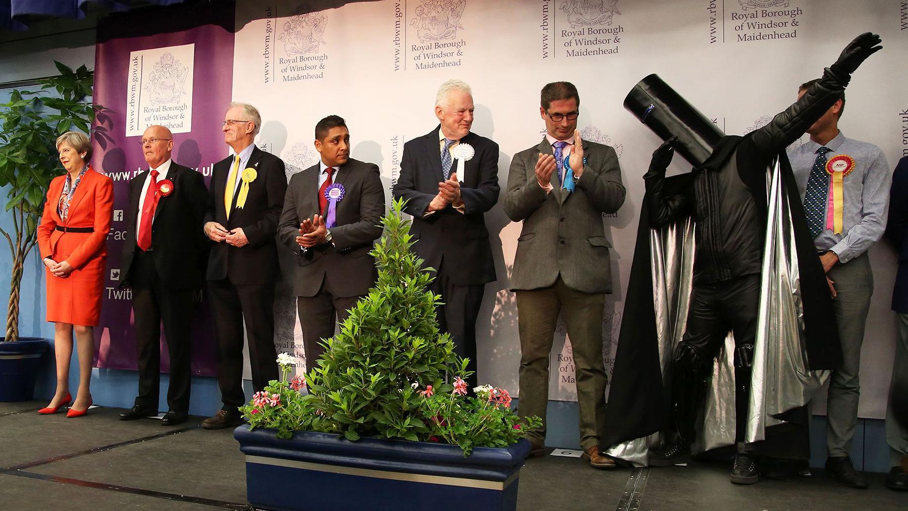 En el escenario durante el recuento de votos, se puede ver a una fila de candidatos. Theresa May se encuentra en el extremo izquierdo y  Lord Buckethead está en el extremo izquierdo levantado un brazo.