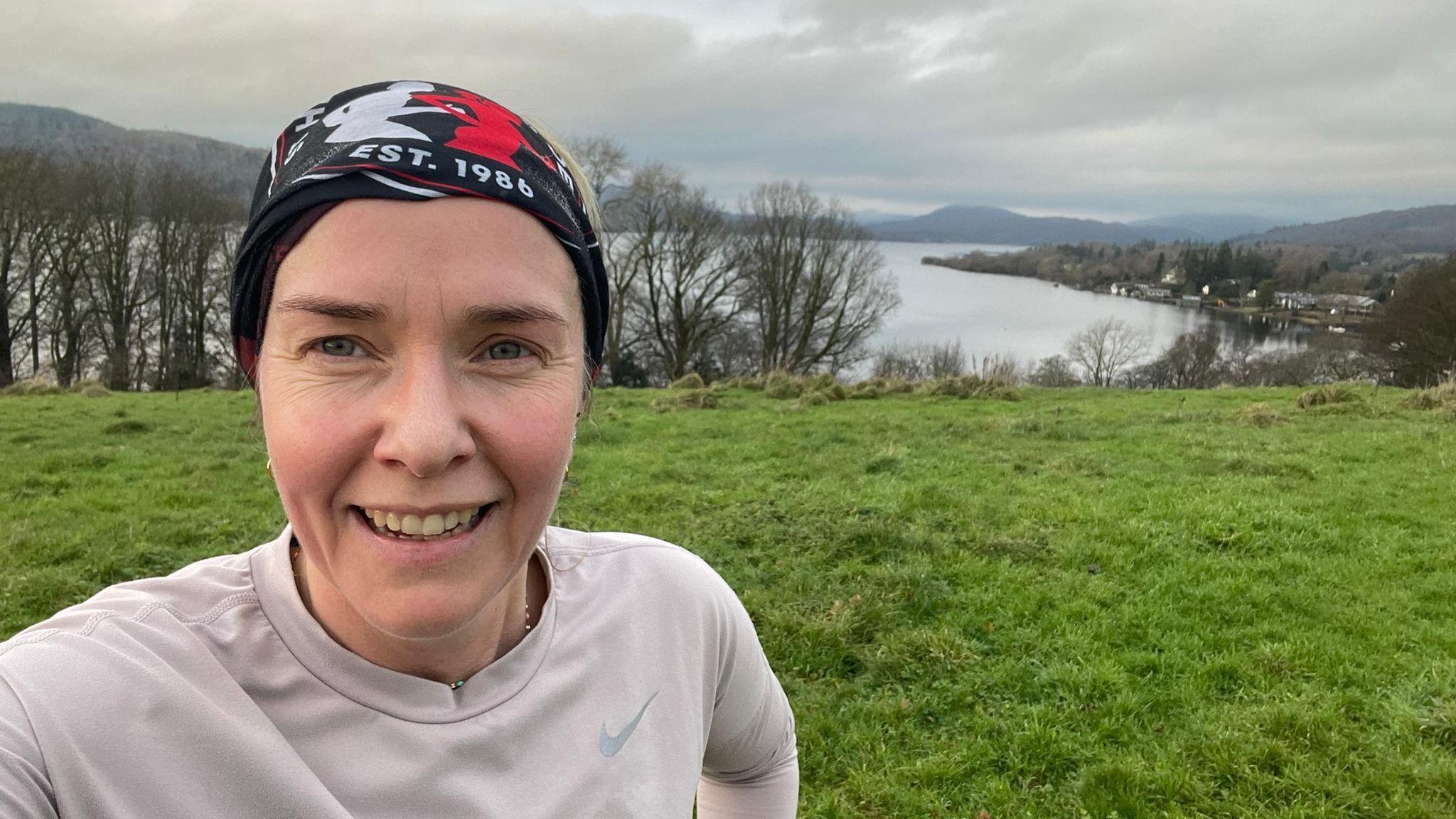 一名頭戴有圖案頭巾的女性在草地與湖泊前自拍