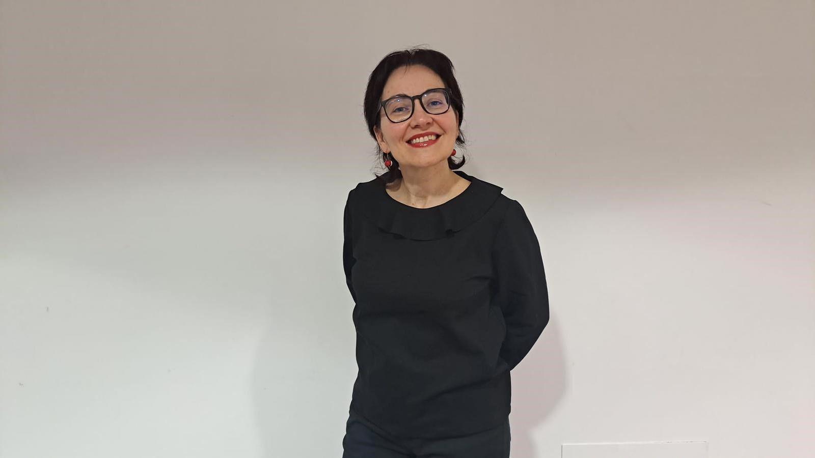 Mulher branca usa óculos e uma blusa preta