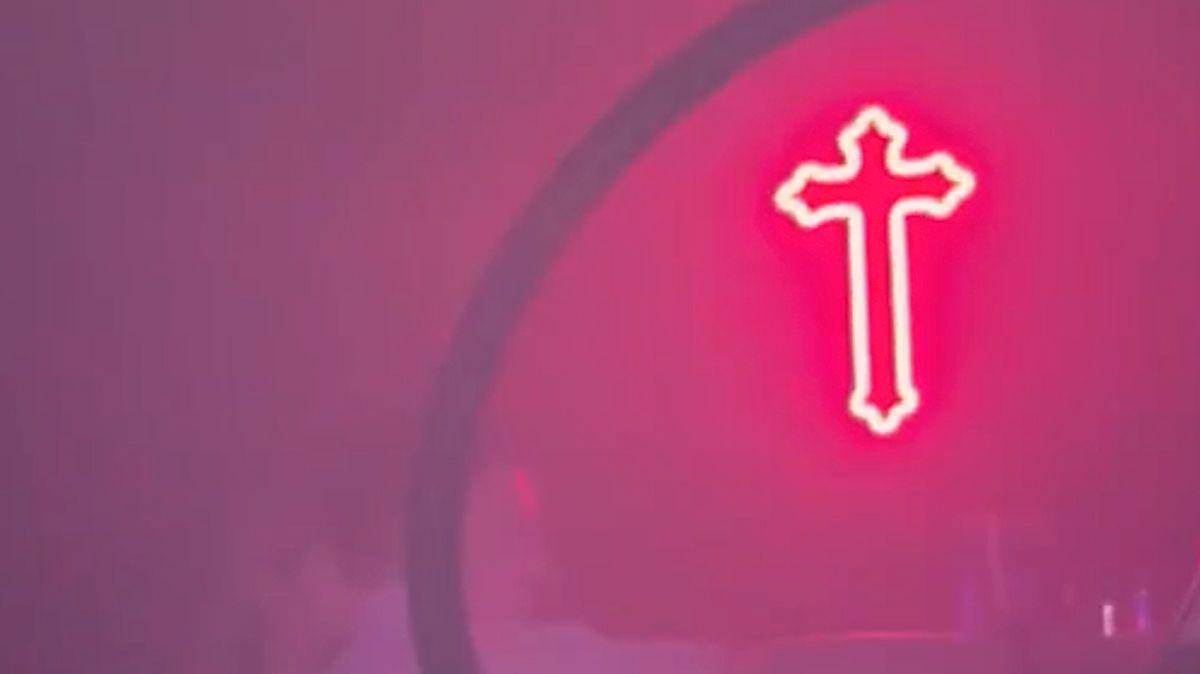  Una luz en forma de cruz de neón rosa colgada en una discoteca.
 