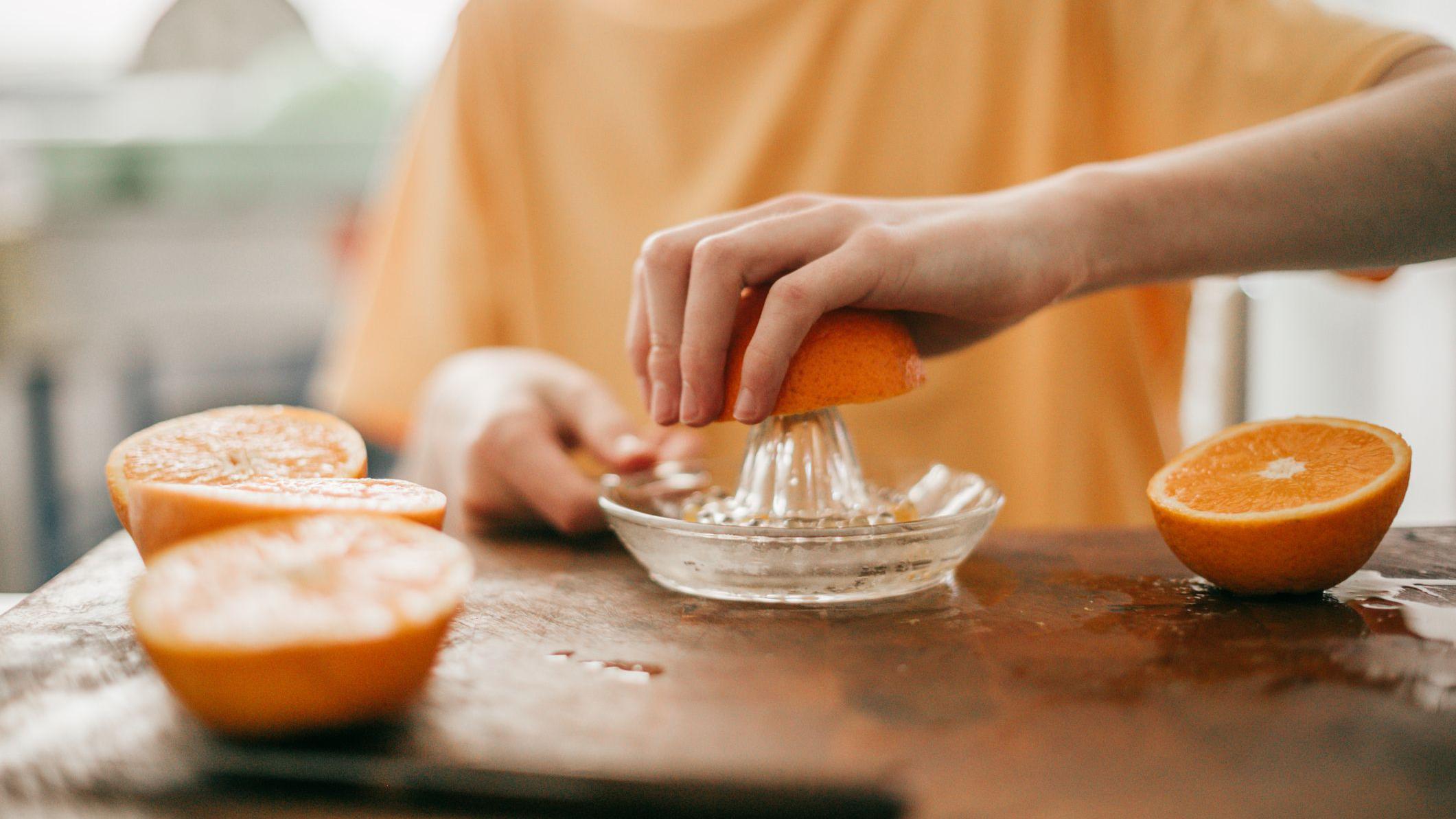 Persona preparando un jugo de naranja. 
