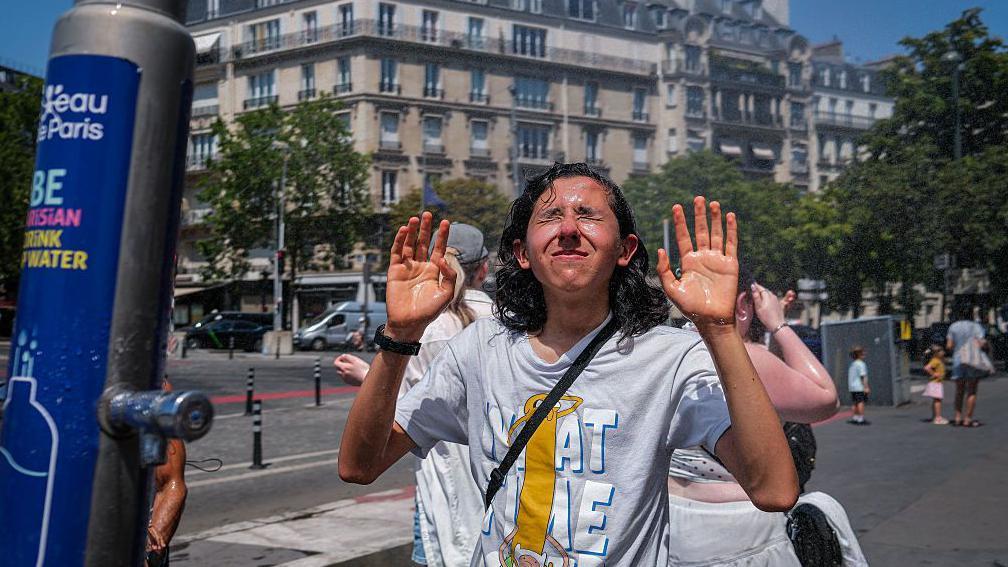 Un joven se refresca en París.