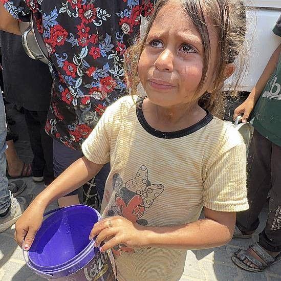 Niña en busca de alimentos con un recipiente vacío 