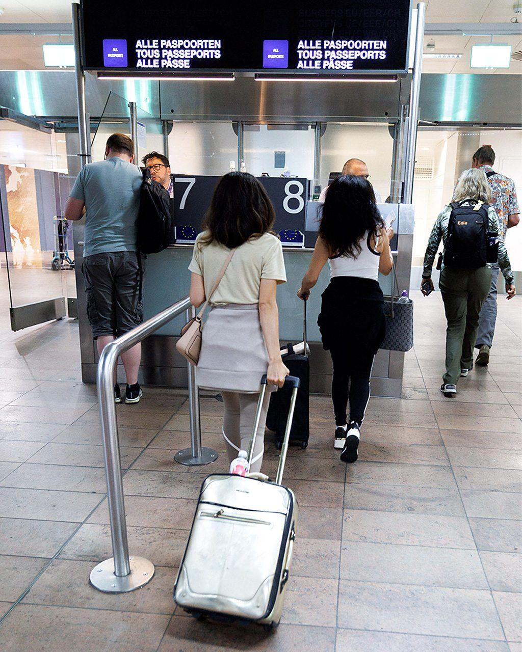 مسافرون مع حقائبهم أمام نافذة ختم الجوازات في المطار.