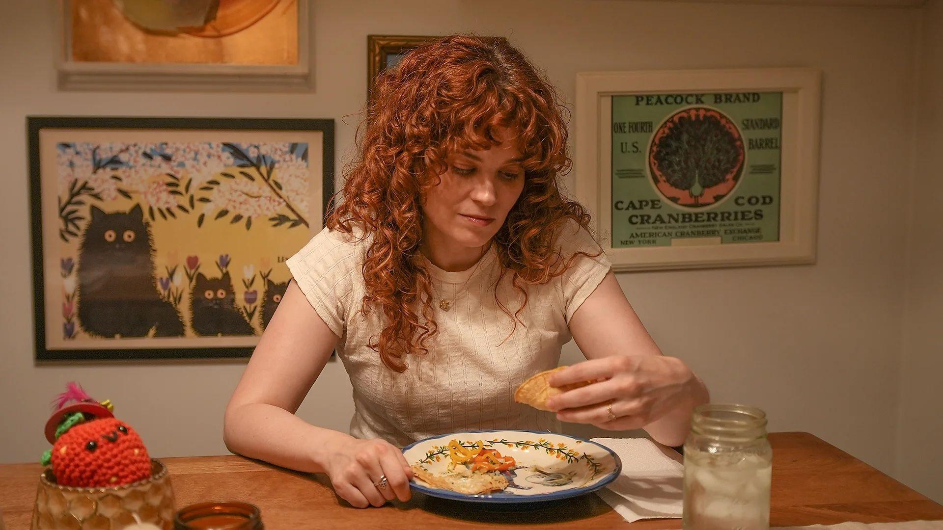 Ally está sentada en el comedor con un plato de comida al frente