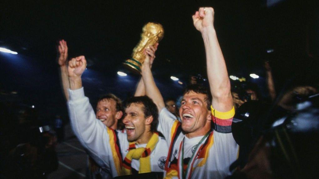 لاعبان من منتخب ألمانيا الغربية الفائزة بكأس العالم 1990 يحملان الكأس
