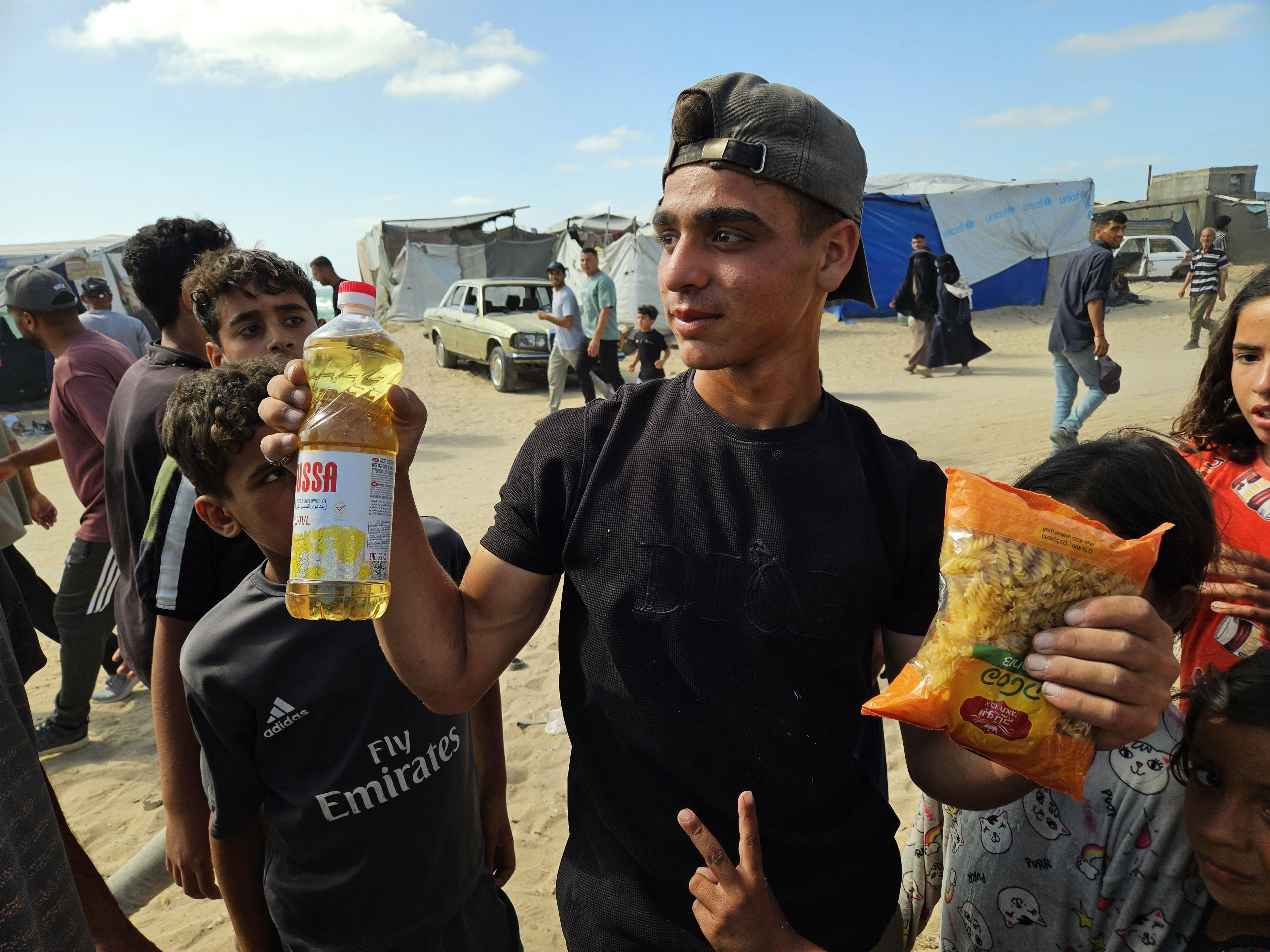Un chico palestino muestra una botella de aceite de cocinar y un kilo de pasta