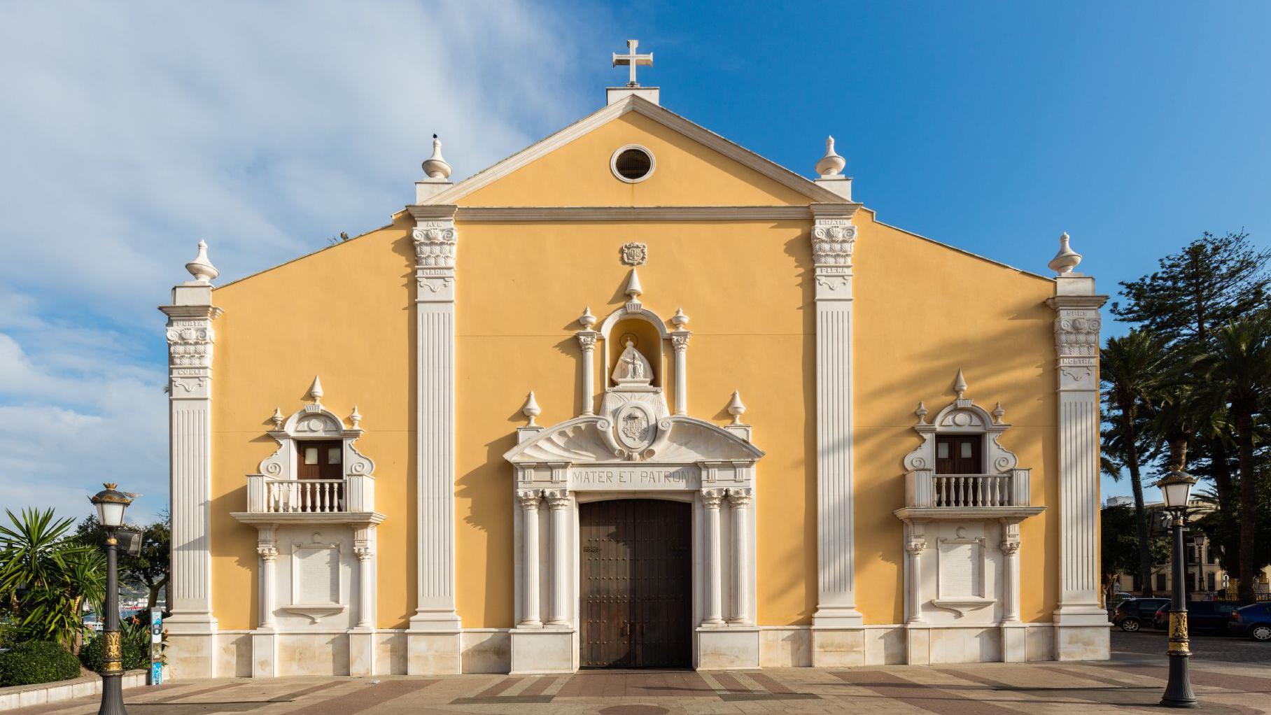 Fachada de uma igreja de estilo renascentista, com paredes amarelas e detalhes ornamentais brancos. O edif&iacute;cio &eacute; sim&eacute;trico, com portal central encimado por uma imagem religiosa, duas pequenas varandas laterais, colunas altas e uma cruz no topo da fachada.