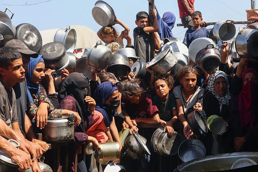 صورة لأطفال ونساء فلسطينيين يحملون أواني فارغةً، ويتكدسون أمام مطبخ خيري في خان يونس، جنوب قطاع غزة في انتظار استلام حصصهم الغذائية.