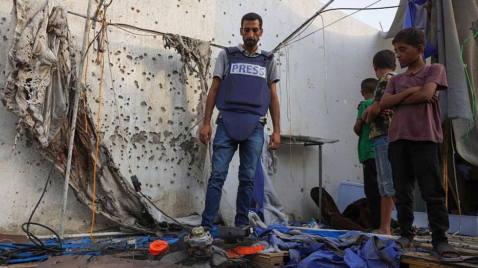 Palestinska deca i novinar proveravaju uništeni šator Al Džazire u blizini bolnice Al-Šifa u gradu Gazi 11. avgusta 2025.