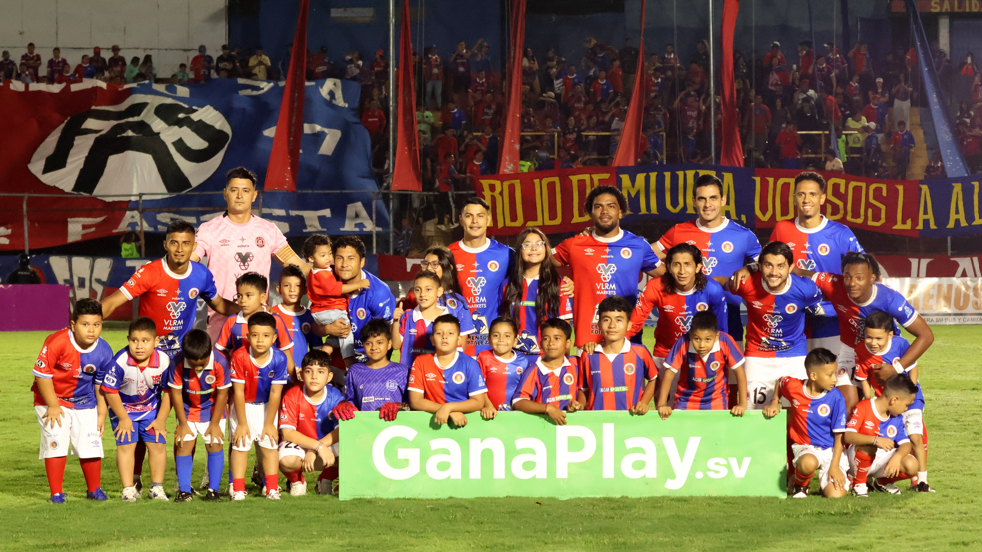 Equipo al completo de FAS posa para la foto con niños antes del partido del sábado 11 de octubre en el Estadio Óscar Alberto Quiteño, el Quiteño, donde los locales enfrentarán a Municipal Limeño, en Santa Ana, El Salvador.