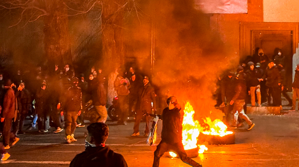 Manifestantes en una calle donde hay unos neumáticos en llamas