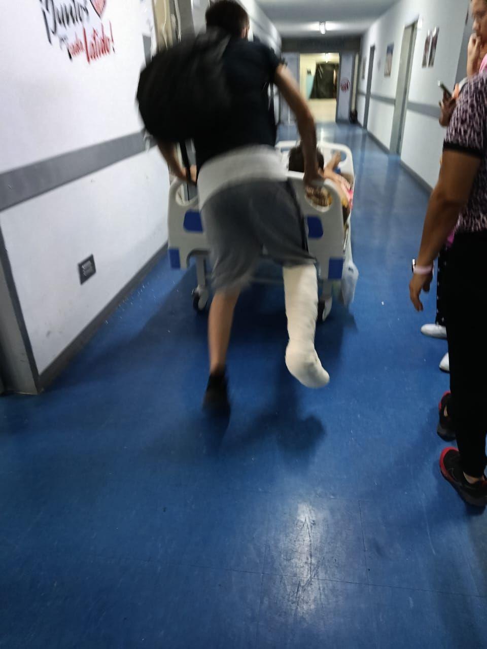 Hombre empuja la cama de un paciente en un hospital de Caracas