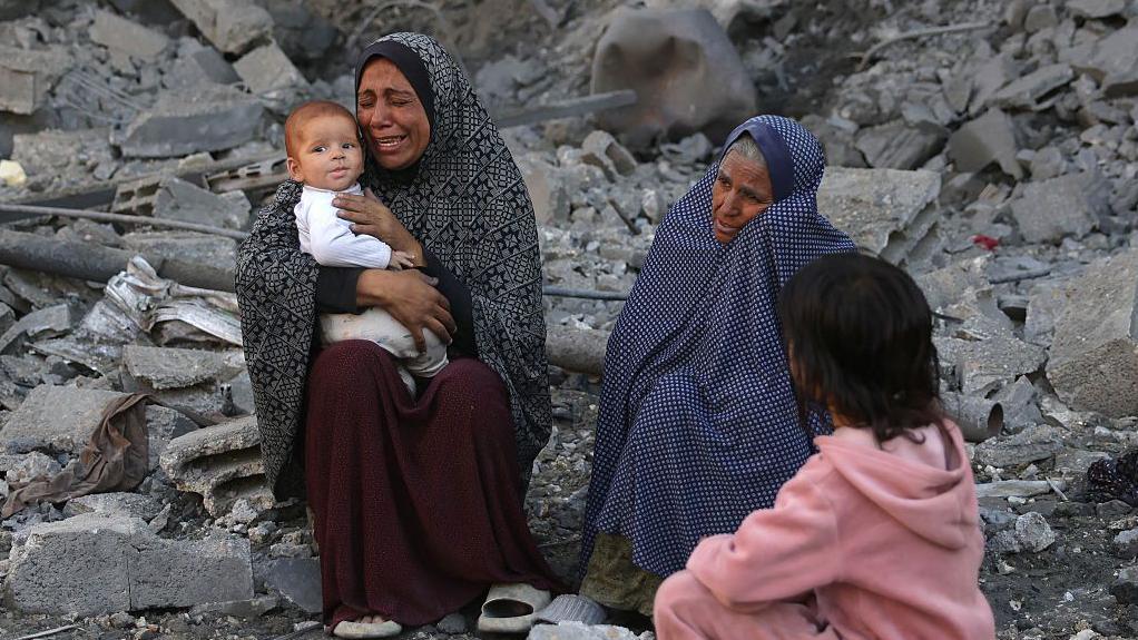 Una mujer con un bebé llora en el lugar de un bombardeo israelí nocturno en Jabalia, en el centro de Gaza, el 30 de mayo de 2025.