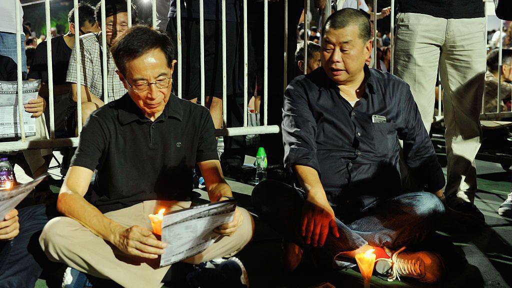 Lai (on the right), in a black shirt, was sitting on the ground behind a lit candle during the 2015 vigil commemorating the 1989 Tiananmen Square crackdown