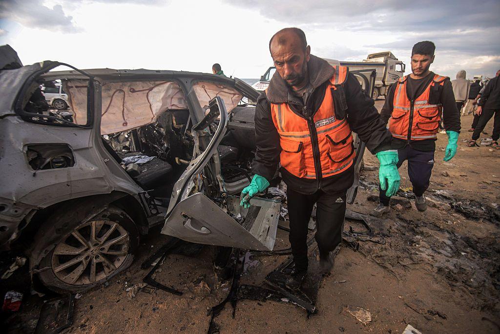 Funcionarios inspeccionan un auto destruido en Gaza.