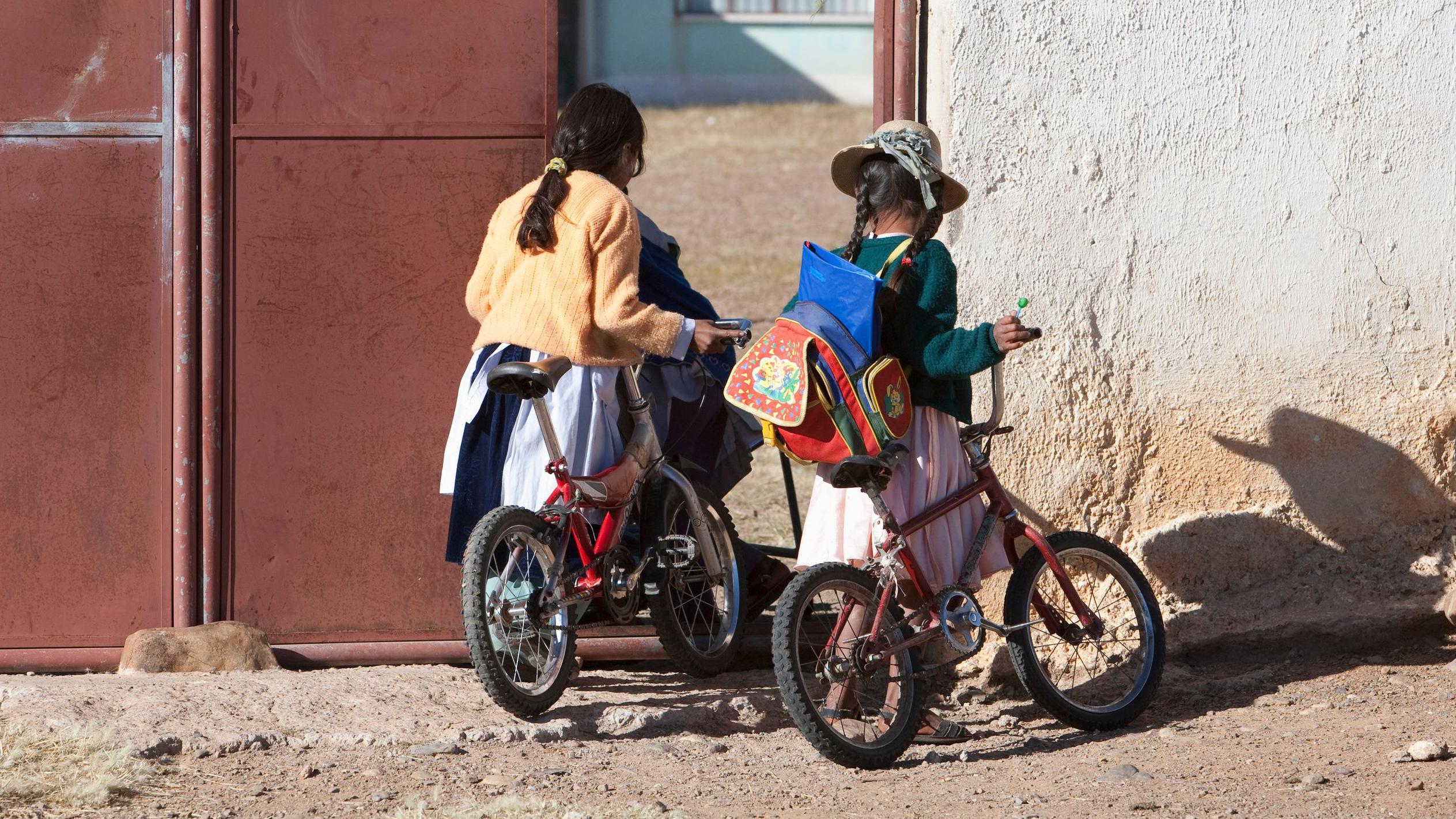 Dos niñas de espaldas en bicicletas en Oruro, Bolivia.