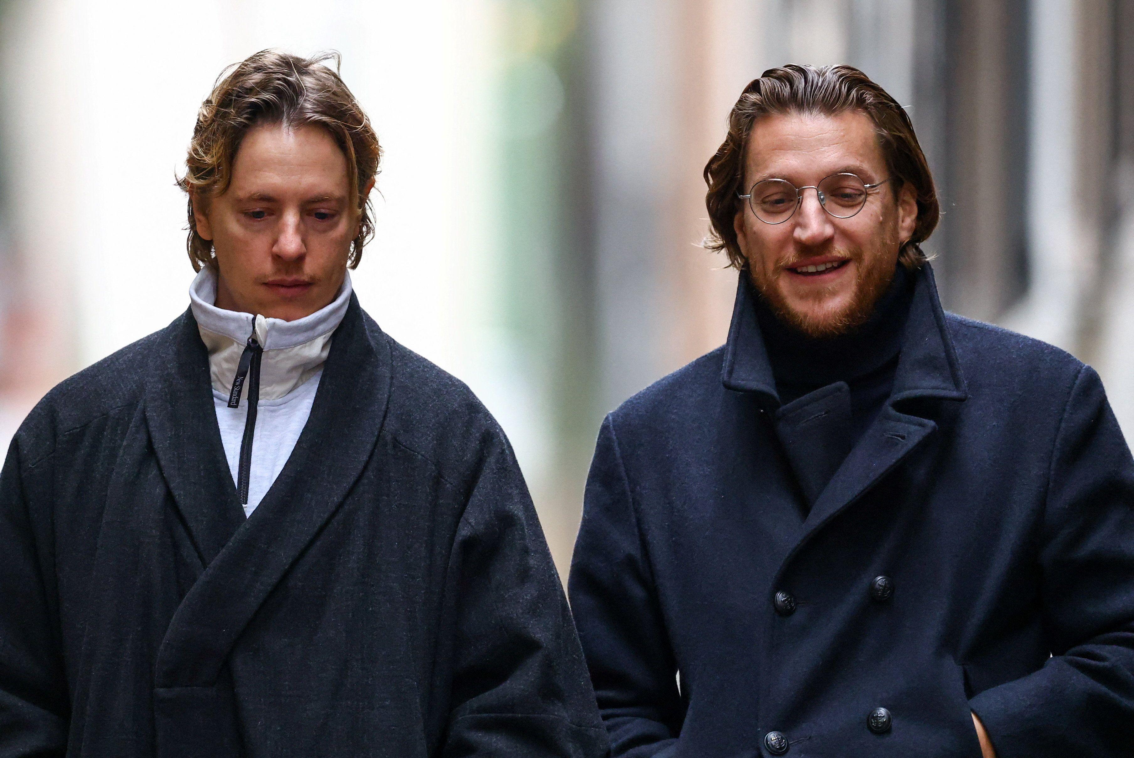 Dos de los hijos de Sarkozy caminan en paralelo. El de la izquierda es rubio y lleva un abrigo. El de la derecha tiene barba y marcha sonriente. 