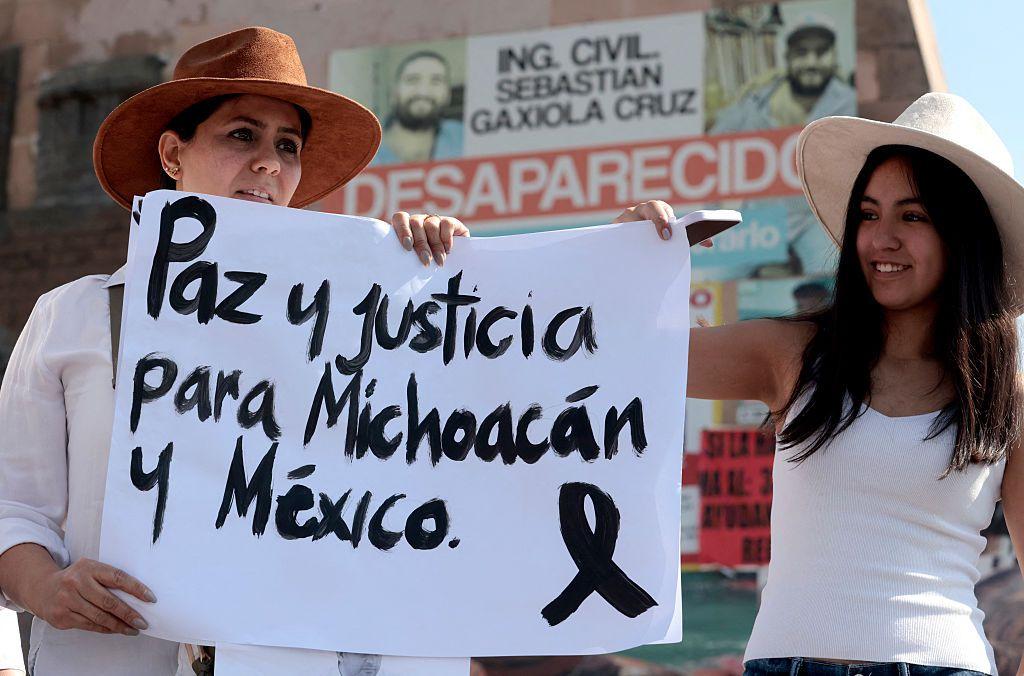 Dos mujeres sostienen una pancarta que dice "Paz y justicia para Michoacán y México" durante la marcha "Por la Paz" organizada por la Generación Z contra el gobierno de la presidenta mexicana Claudia Sheinbaum en Guadalajara, Jalisco, México, el 15 de noviembre de 2025. Miles de personas marcharon por las calles de la Ciudad de México el sábado para protestar contra la violencia de las drogas y las políticas de seguridad del gobierno de la presidenta Claudia Sheinbaum. (Foto de ULISES RUIZ / AFP) (Foto de ULISES RUIZ/AFP vía Getty Images)