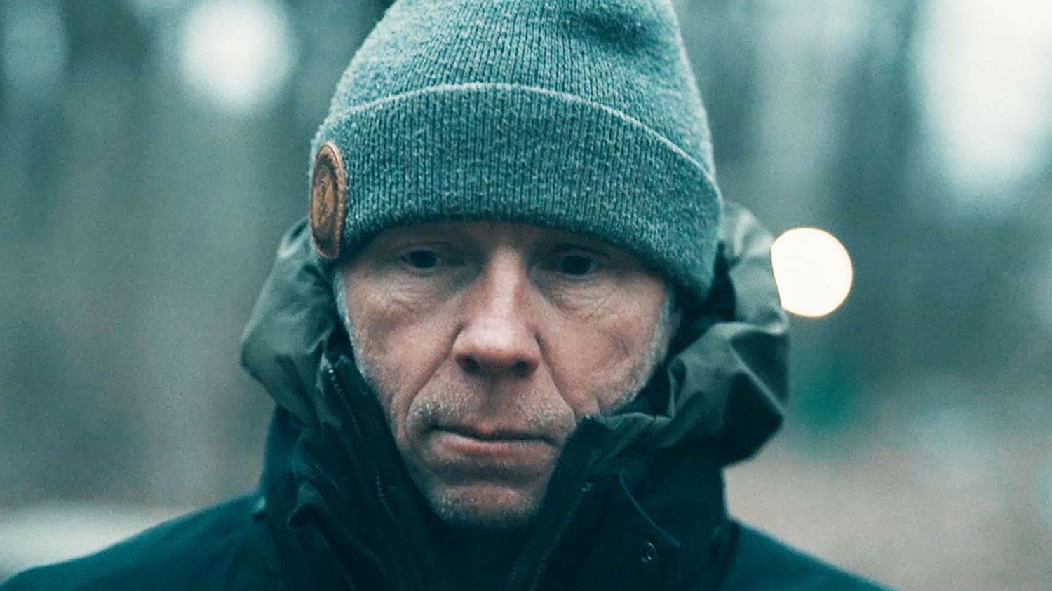 mupkarac sa kapom na glavi i u jakni gleda u prazno