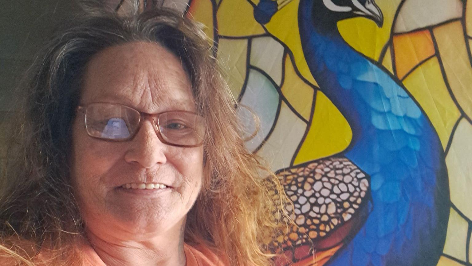 Krystal DuFrene está em frente a um painel de porta com um pavão azul.