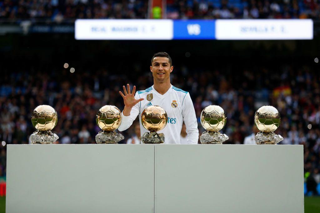 Cristiano Ronaldo mostra o n&uacute;mero cinco com uma das m&atilde;os. Na frente dele est&atilde;o cinco bolas de ouro