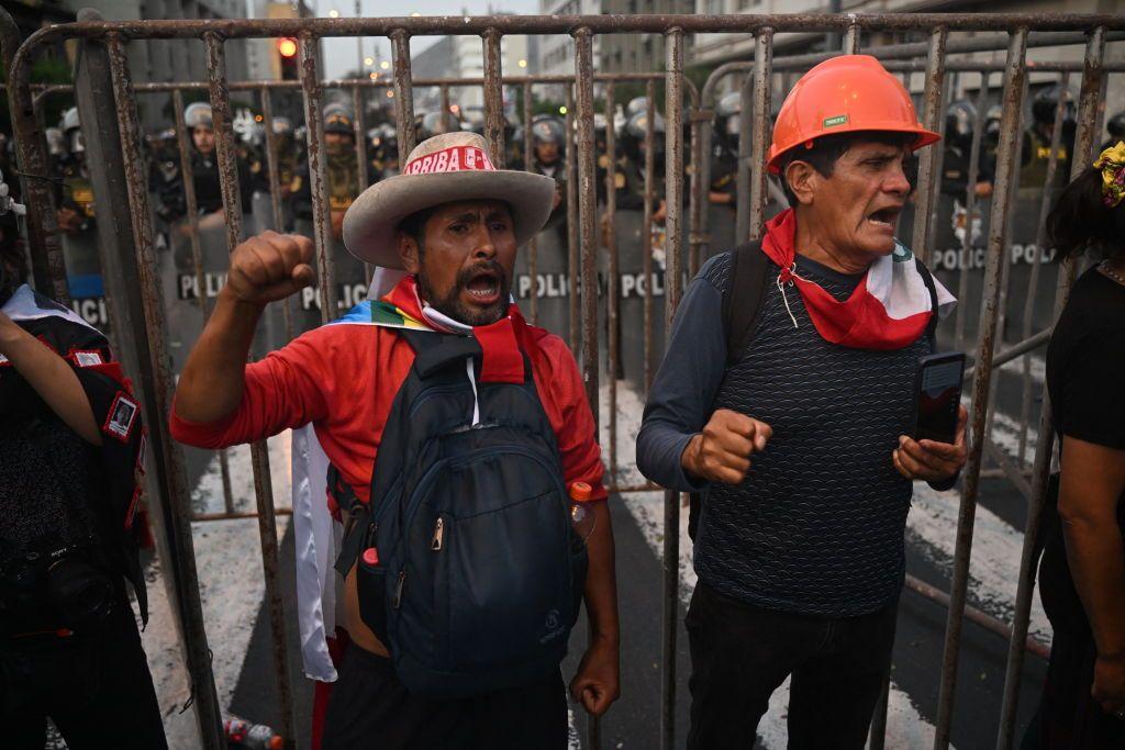 Dos personas gritan junto a una valla colocada por la Policía en el centro de Lima. 