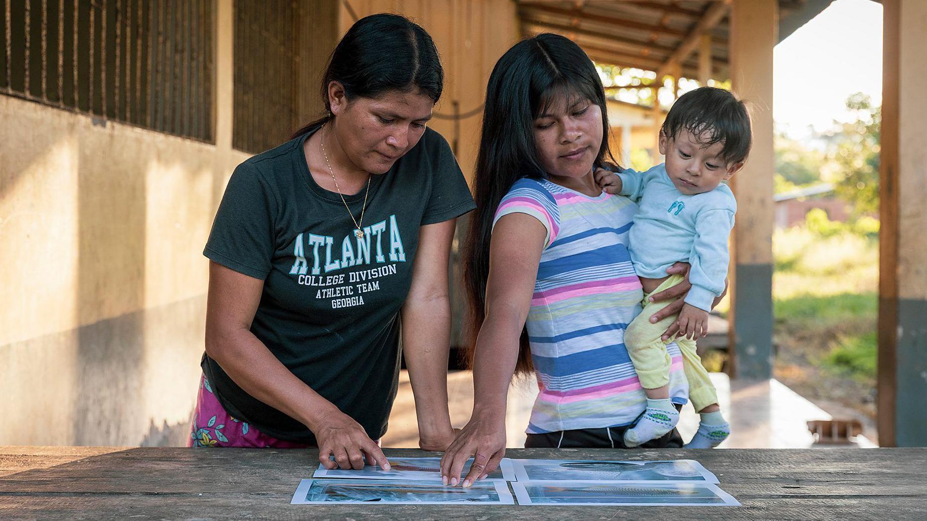 أفراد من المجتمع المحلي مع صور للأسماك التي اكتشفوها