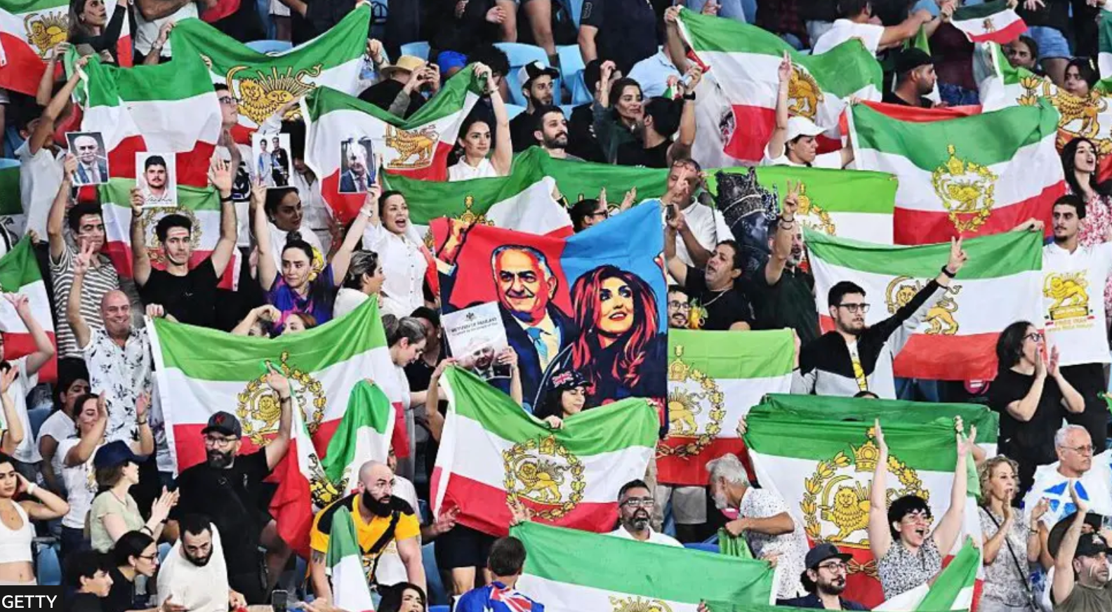 مشجعون إيرانيون يلوّحون بأعلام غير رسمية وصور لرضا بلهوي الابن خلال مباراة إيران والفلبين 