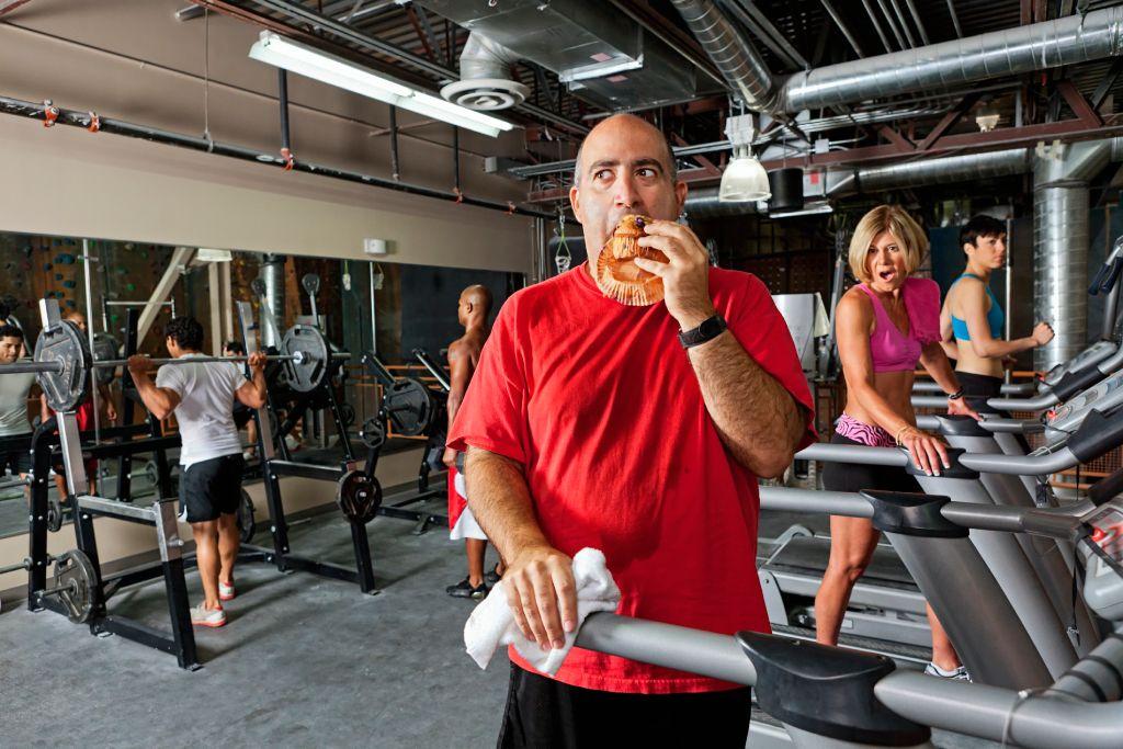Hombre comiendo pastel en gimnasio