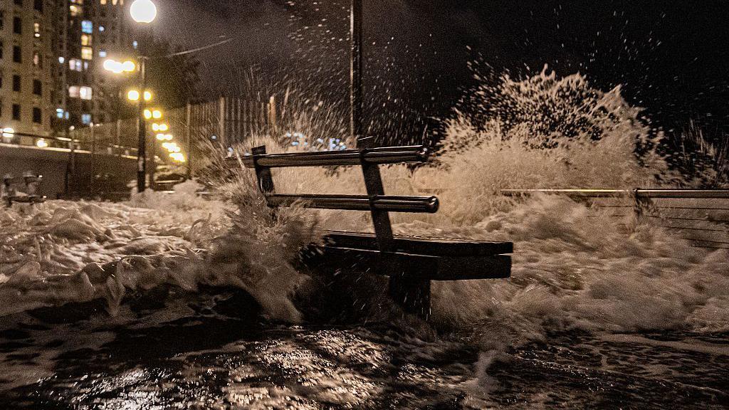 El mar golepa un banco situado en un paseo marítimo.