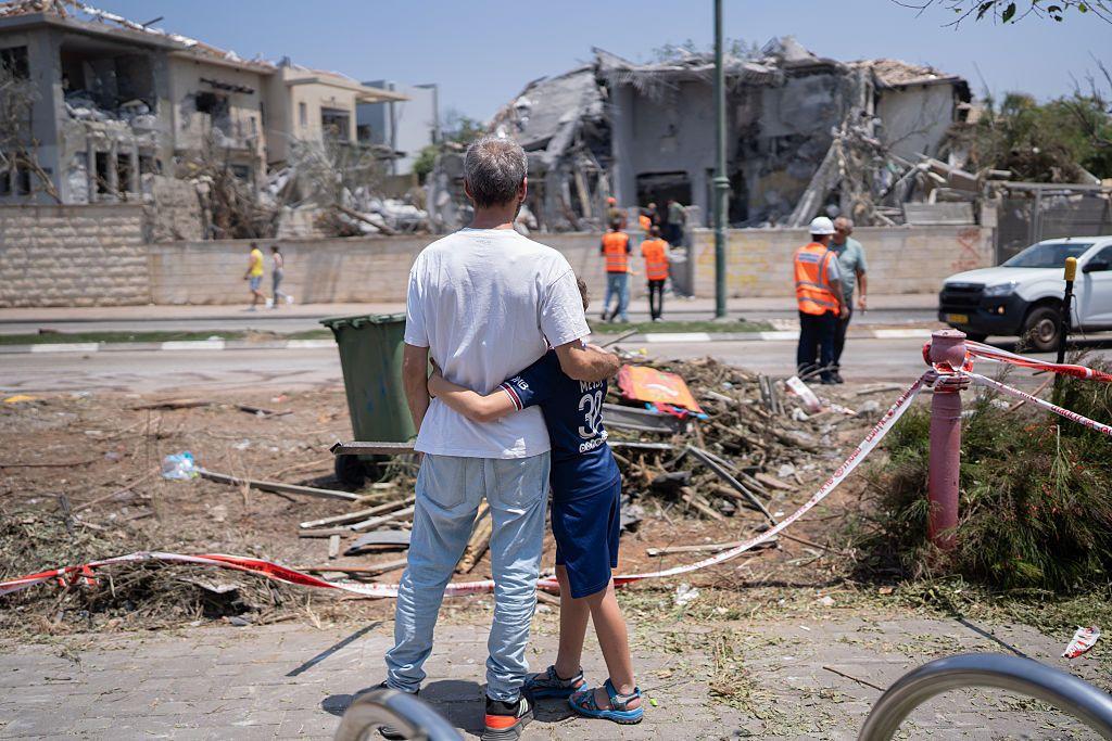 Un padre y su hijo frente a su casa destruida.