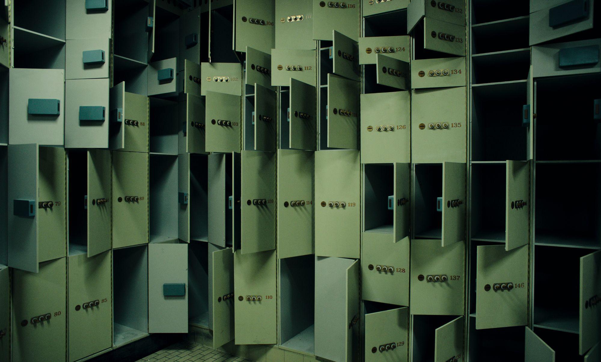 Fila de casilleros metálicos abiertos y vacíos, con cerraduras visibles en una sala iluminada