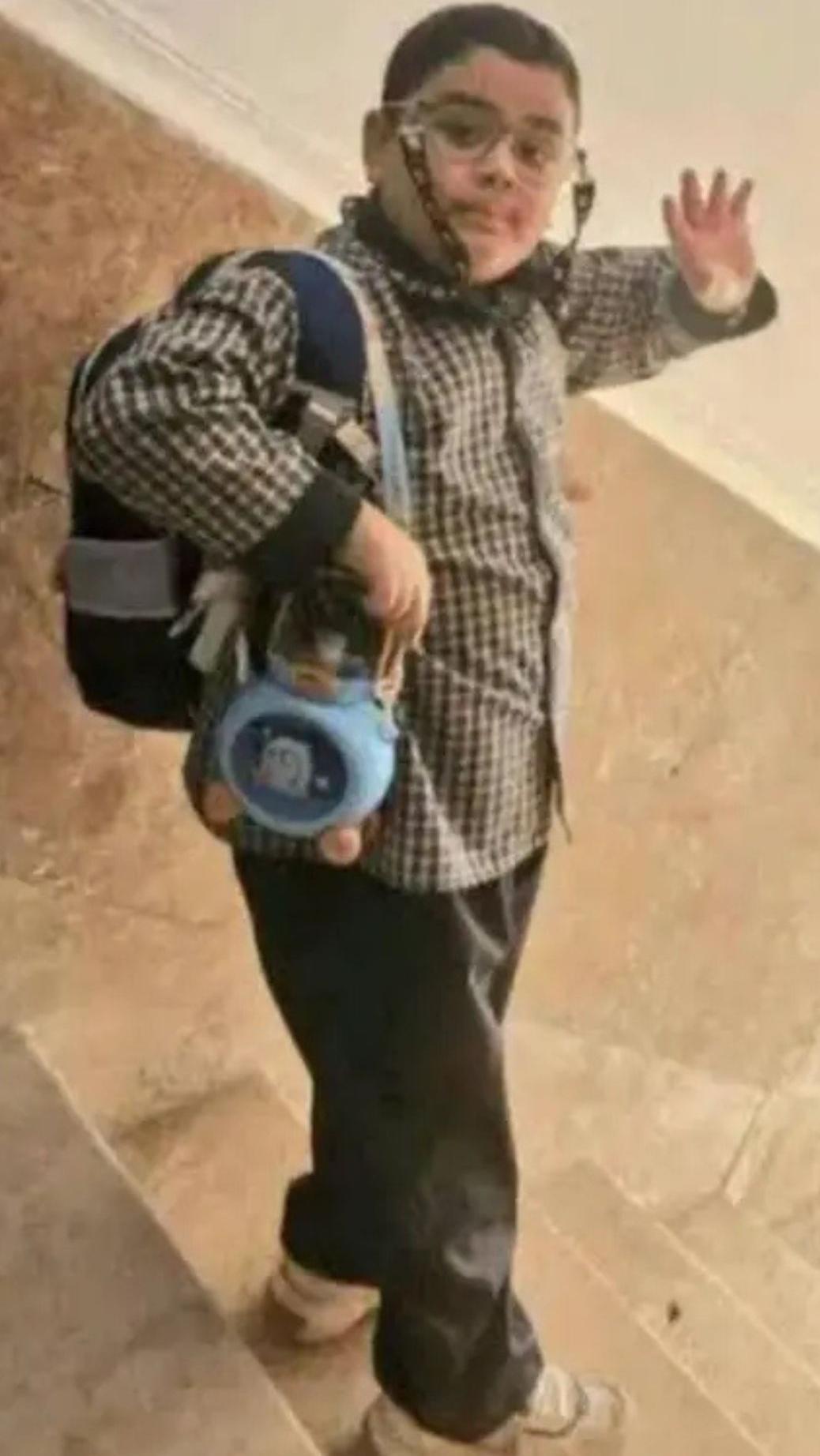 En la última foto de Michael se le ve girándose para saludar a la cámara mientras baja por unas escaleras; lleva una mochila escolar, una camisa a cuadros marrón, pantalones a juego, zapatillas blancas, gafas, ojos marrones y el pelo corto.