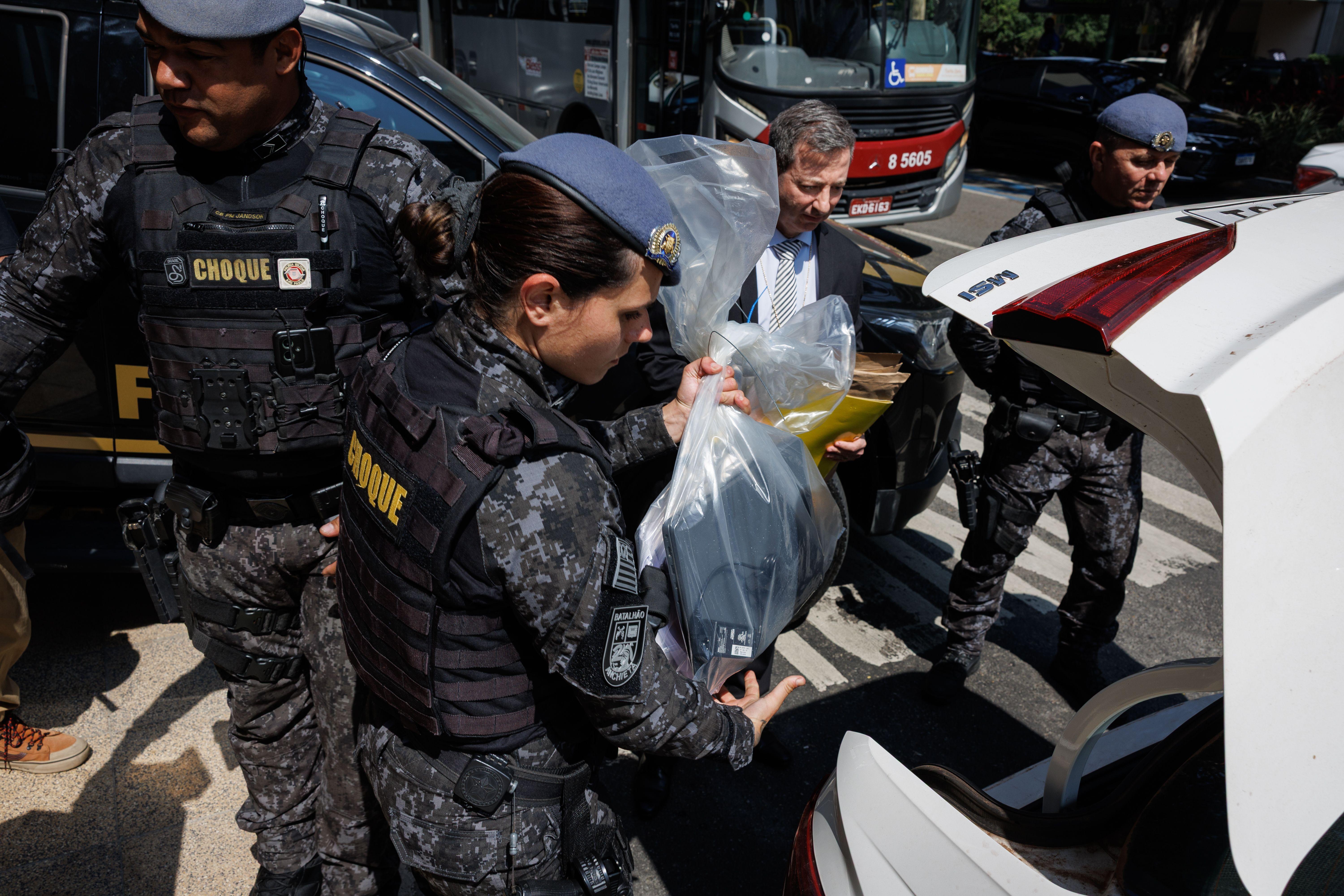 Policial fazendo apreensão e colocando sacola em carro