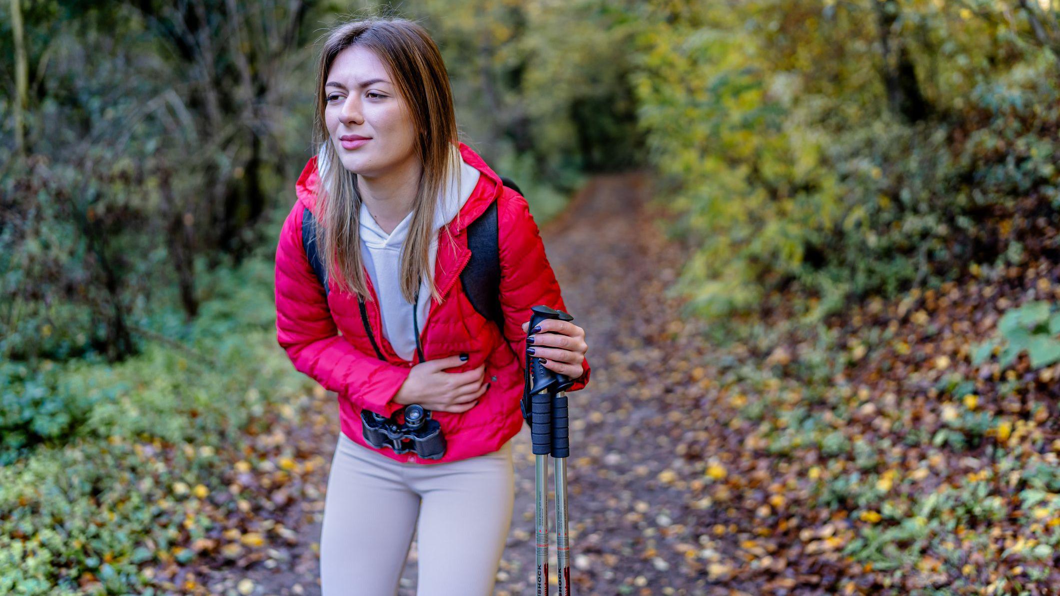 Una joven paseando por el bosque con dolor de estómago