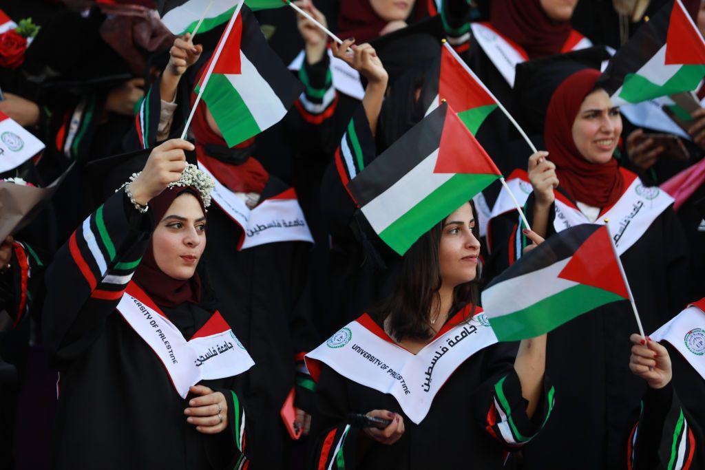 طالبات الفلسطينيات يرتدين أثواب التخرج ويحملن الأعلام الفلسطينية في حفل تخرجهن من جامعة فلسطين وسط قطاع غزة 