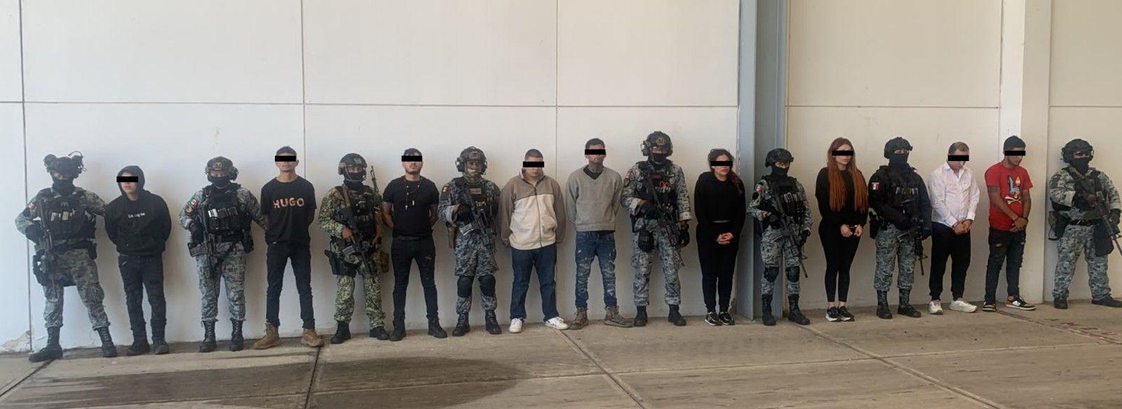 Policías y detenidos posan frente a una pared