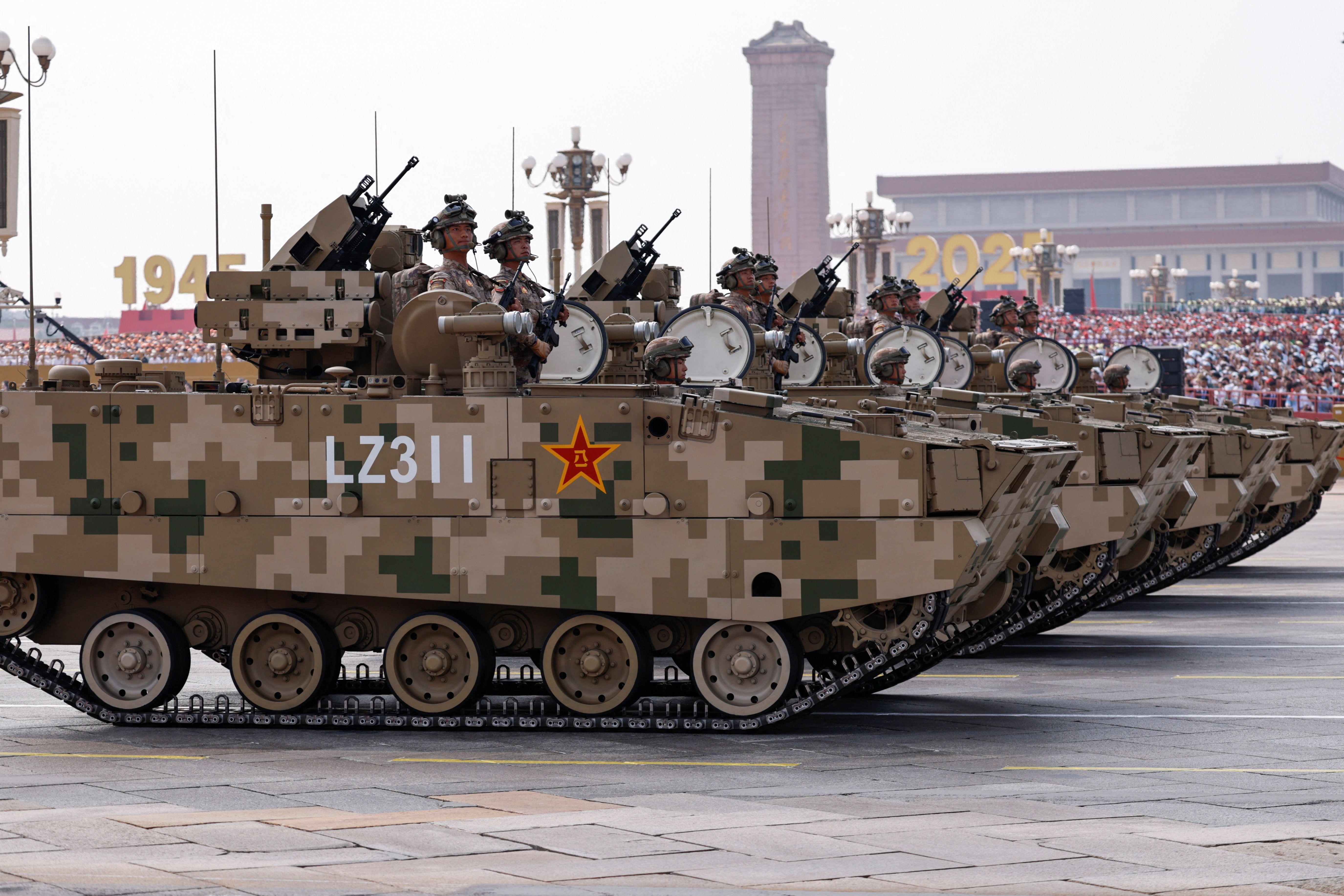 Miembros de la Fuerza de Asalto Terrestre del Ejército Popular de Liberación se encuentran de pie sobre vehículos blindados durante un desfile militar.