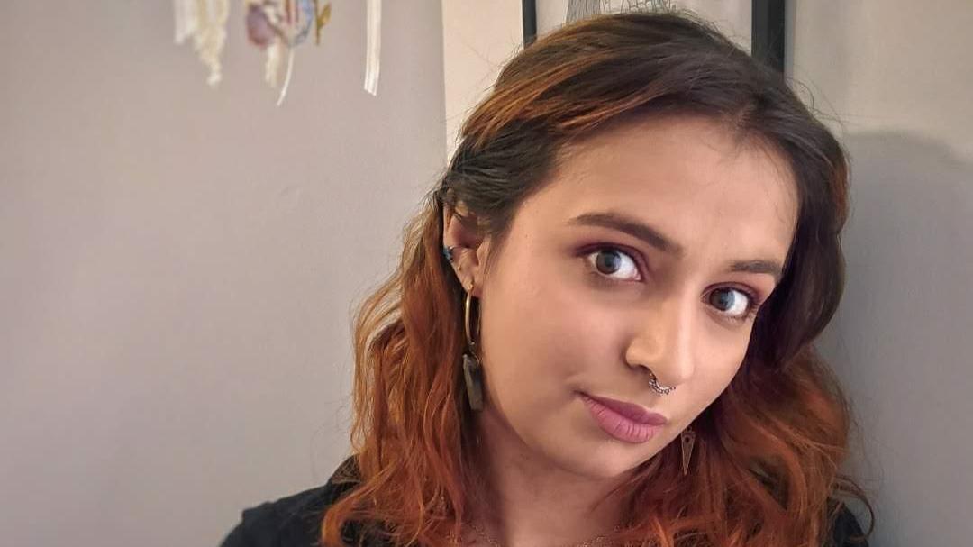 Catalina mira a la cámara con su cabeza inclinada hacia la derecha mientras mantiene una expresión seria en su rostro.