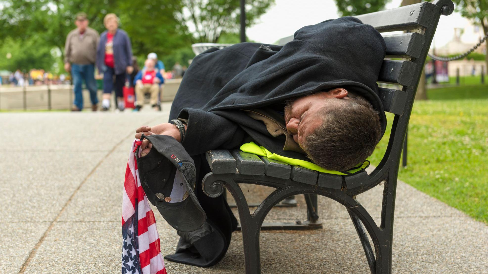 Un hombre durmiendo en una banco de Washington DC.