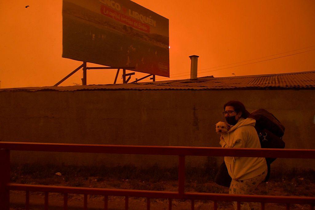 Una residente evacúa su casa con su perro durante un incendio forestal en Concepción, Chile, el 18 de enero de 2026.