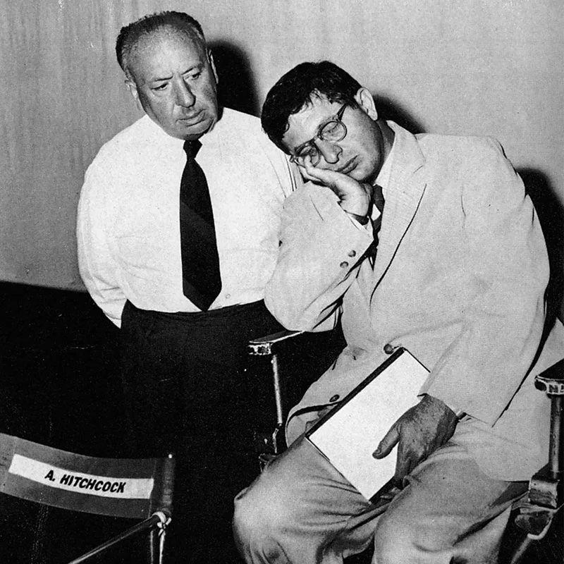 Hitchcock olha para Herrmann sentado em uma cadeira dormindo com a mão no rosto