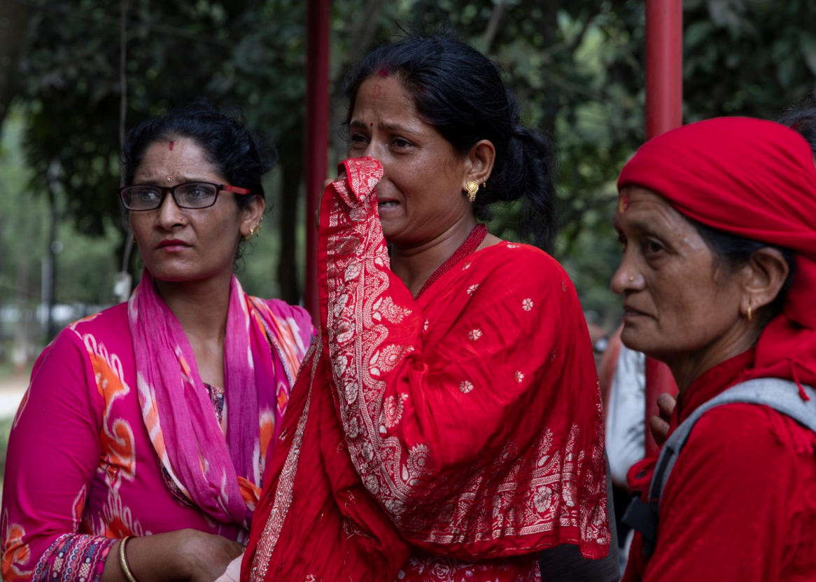 Tres mujeres se lamentan afuera de un hospital tras las avalanchas en Trishuli Bazar