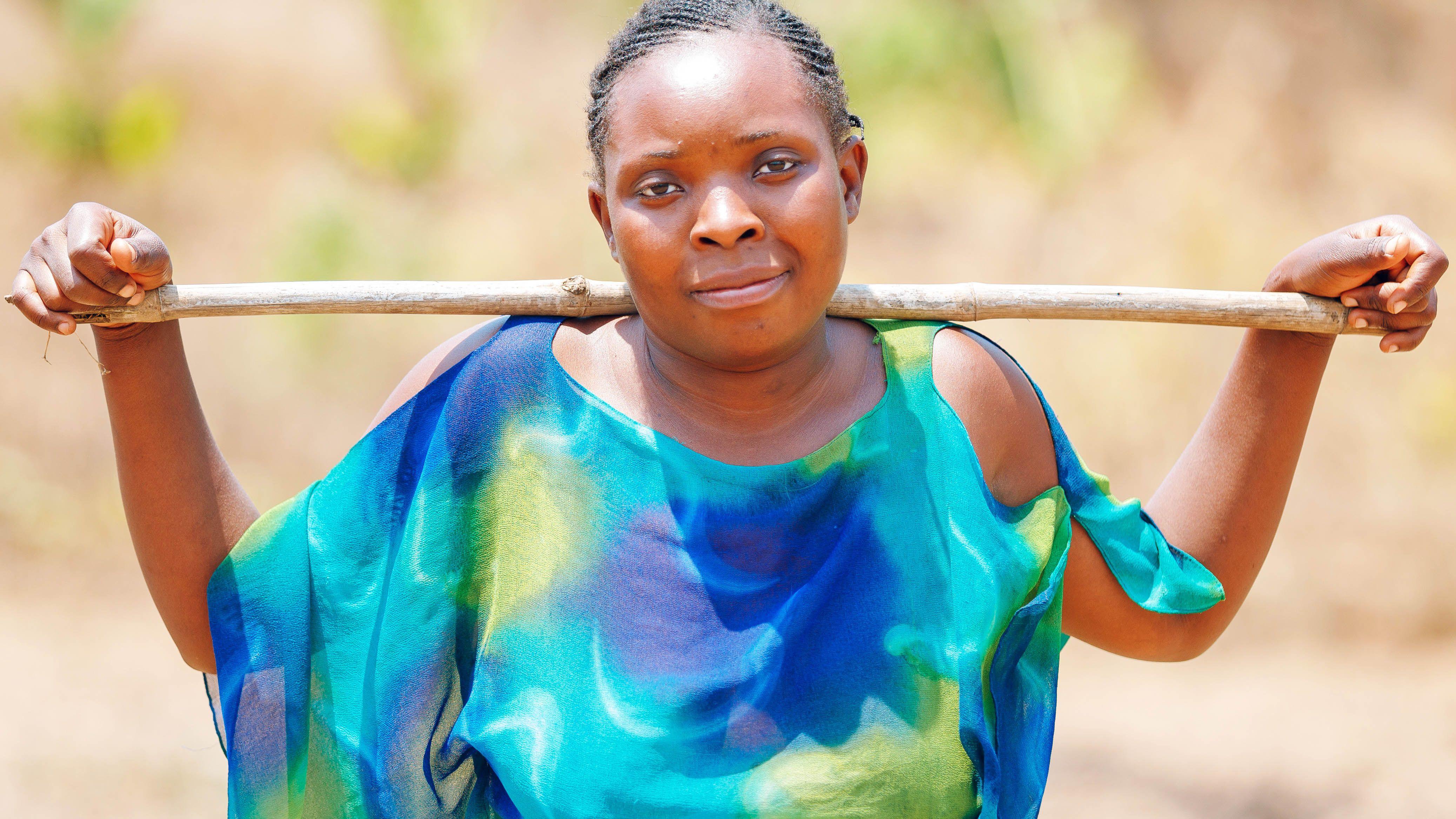 28歲的特瓦利馬村的農民阿比蓋爾·南托韋肖像。她對著鏡頭露出含蓄的微笑，並將一根長木棍橫放在肩胛骨上，雙手搭在木棍上。她身穿一件藍綠相間、飄逸的上衣。